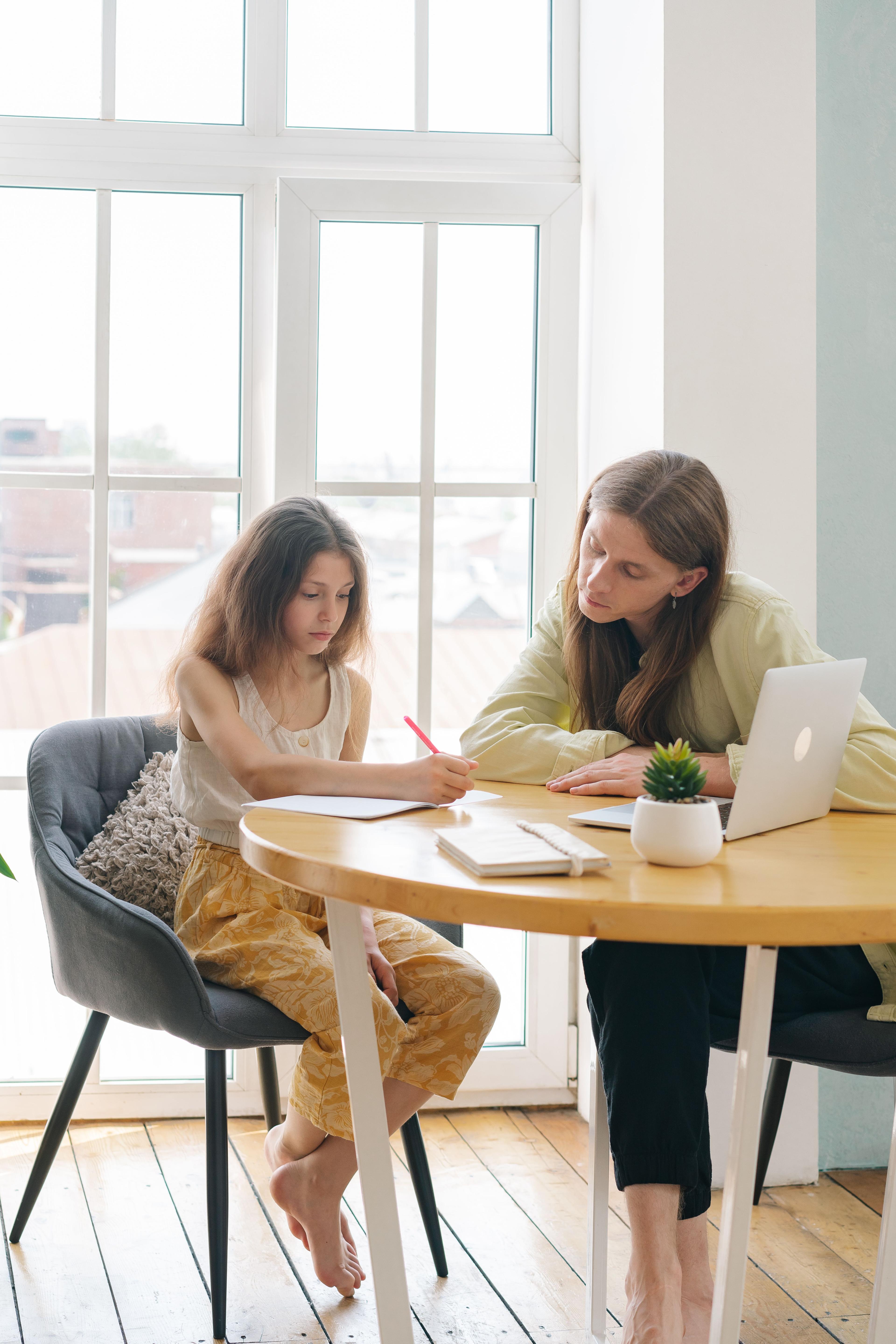 Mentor en leerling werken samen aan een rustige tafel bij het raam